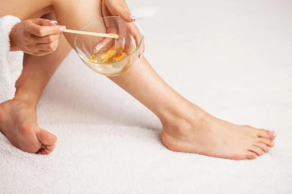 Woman applying wax on legs for hair removal